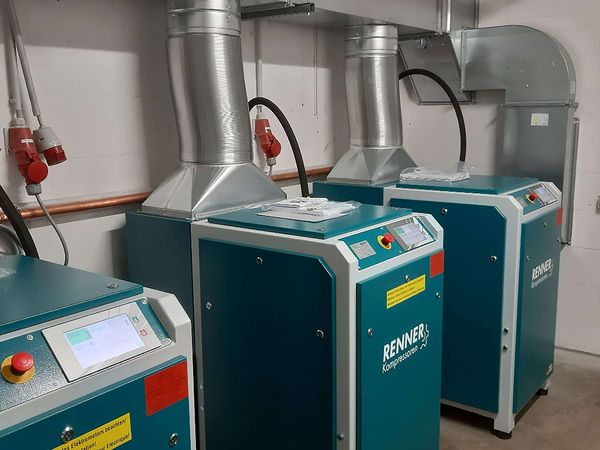 Kompressor-Anlage mit Belüftung – Drei RENNER-Druckluftkompressoren mit Lüftungsrohren in einem Technikraum