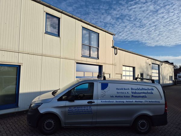 Firmenfahrzeug mit blauer Aufschrift steht vor dem Firmengebäude